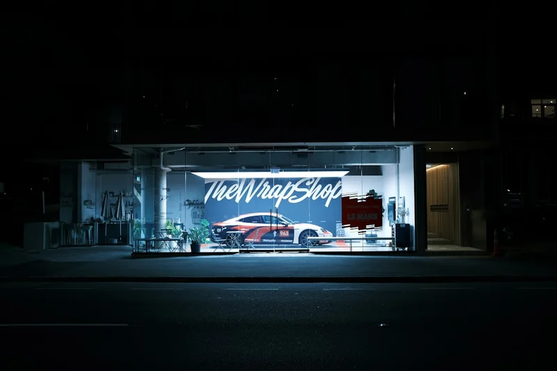 A red sports car inside the wrap shop at night